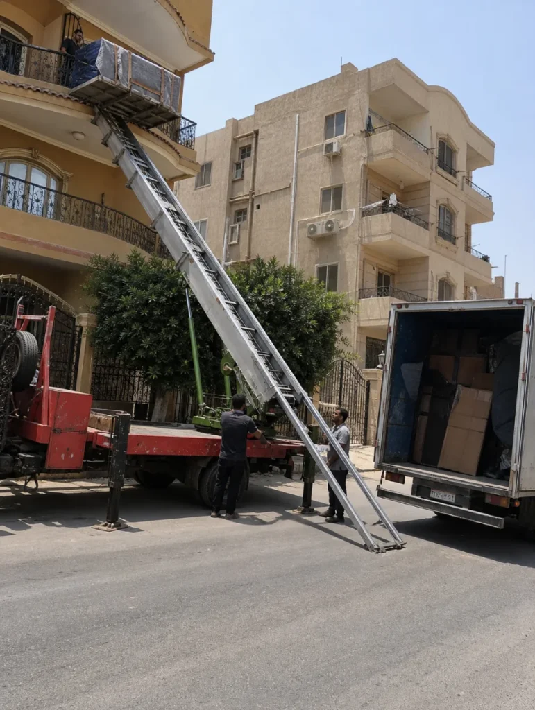 ونش رفع أثاث مع شاحنة نقل بجانب مبنى سكني